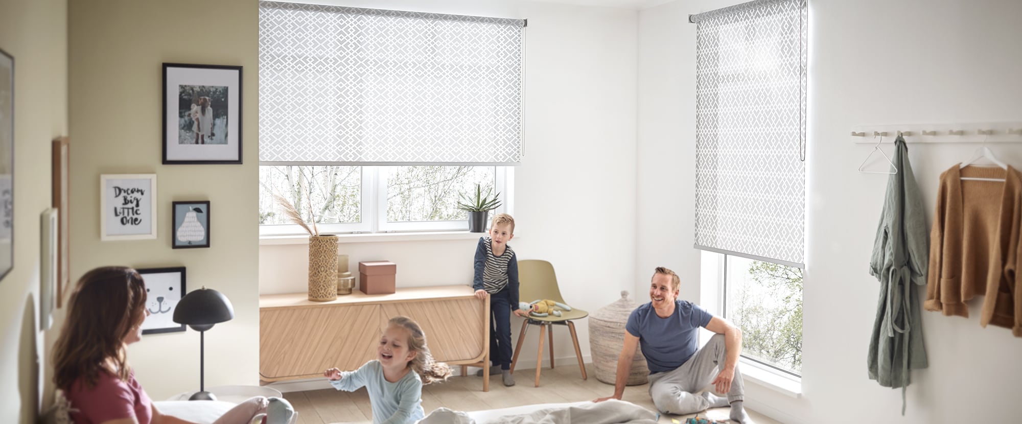 Familie sitzt im Schlafzimmer mit einem KADECO Rollo in Designausführung als grauer, zeitloser Sichtschutz