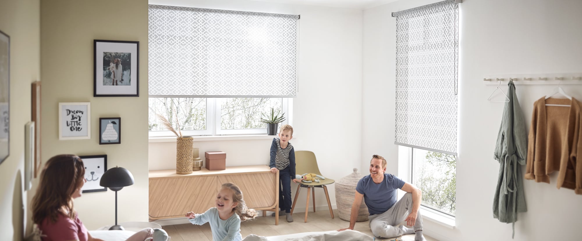 Familie sitzt im Schlafzimmer mit einem KADECO Rollo in Designausführung als grauer, zeitloser Sichtschutz
