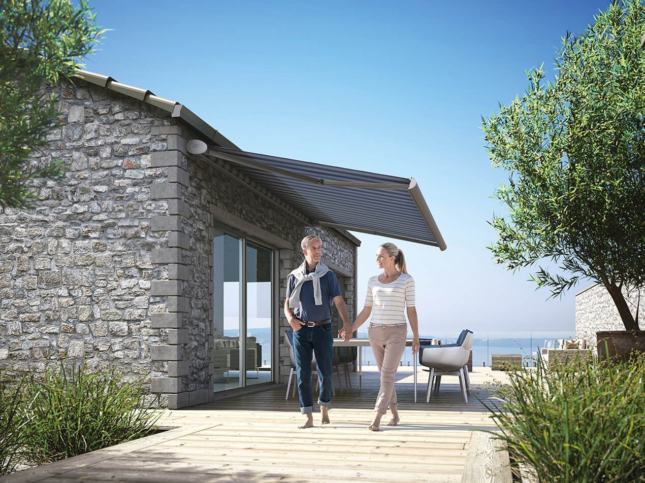 Ein Paar geht unter ihrer KADECO Terrassenmarkise entlang