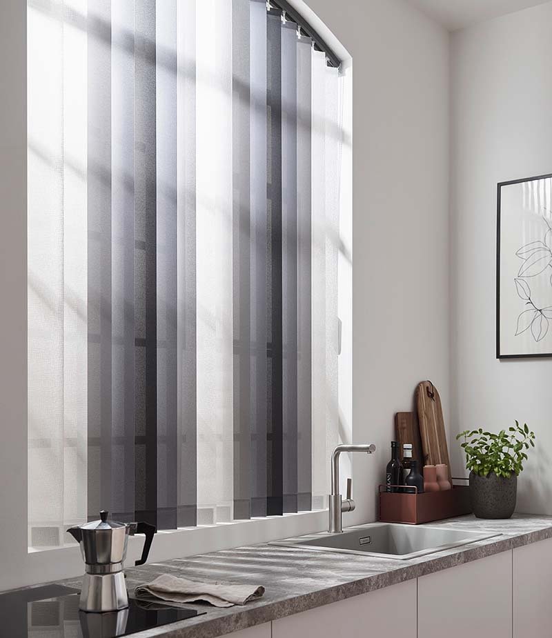 Gebogener Lamellenvorhang in grau und weiß vor Küchenfenster